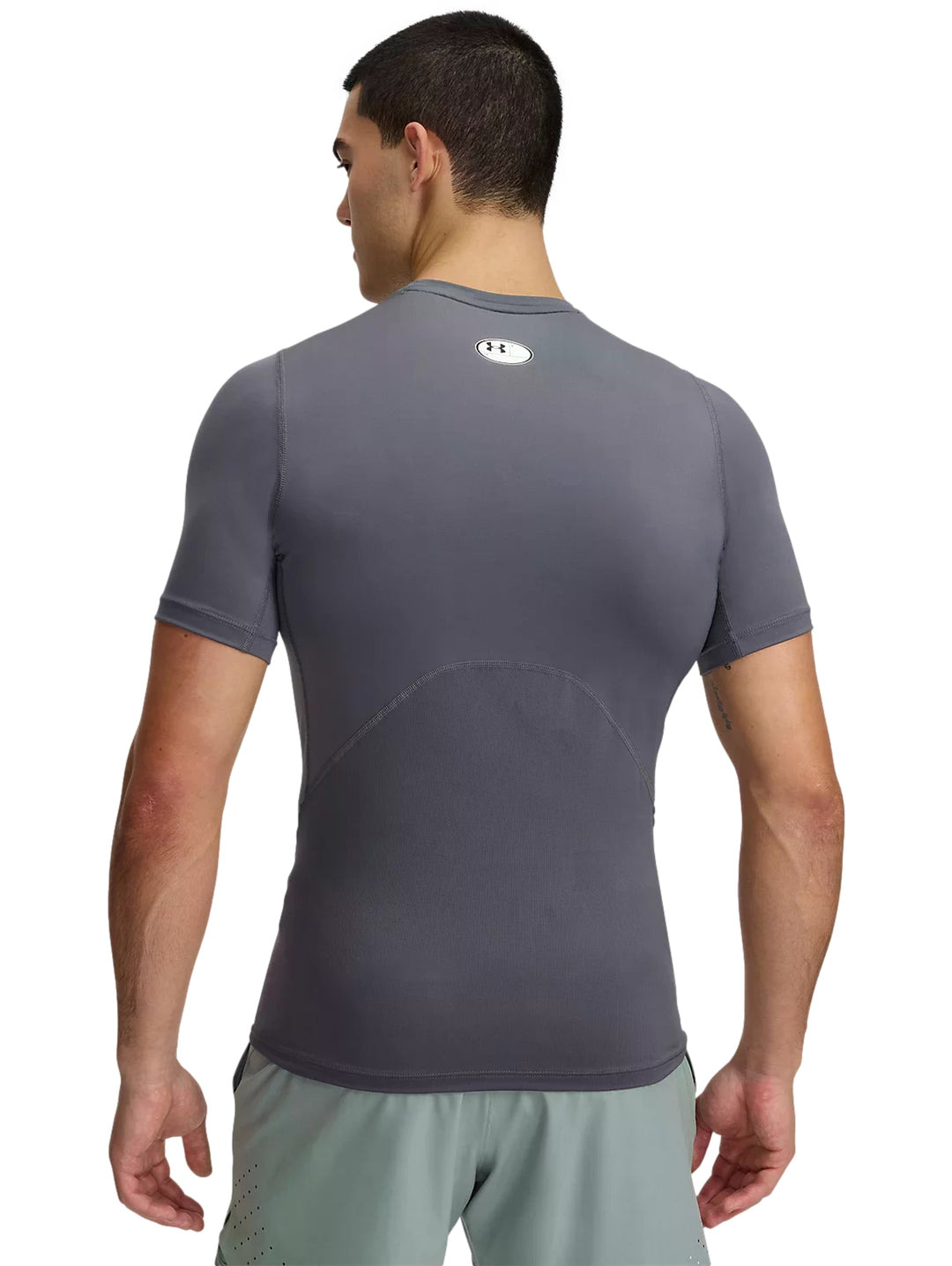 Hombre usando playera de compresión gris Under Armour y shorts deportivos verde claro.