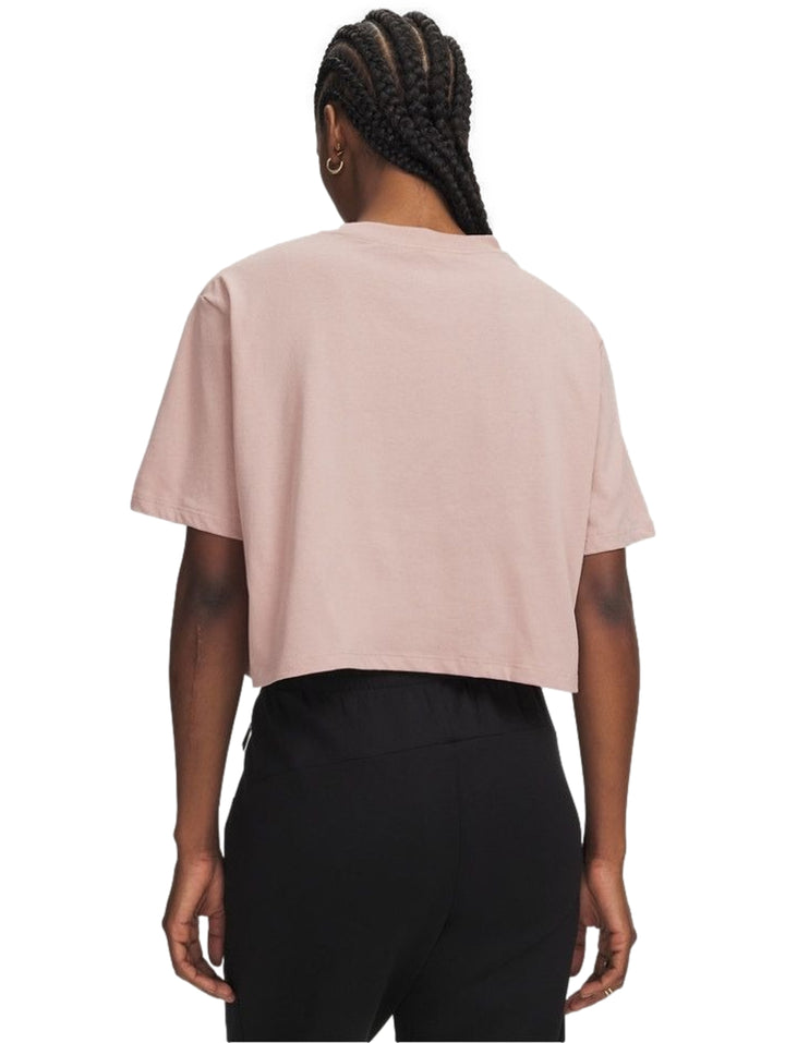 Mujer vistiendo playera rosa Under Armour de manga corta y pantalones negros.