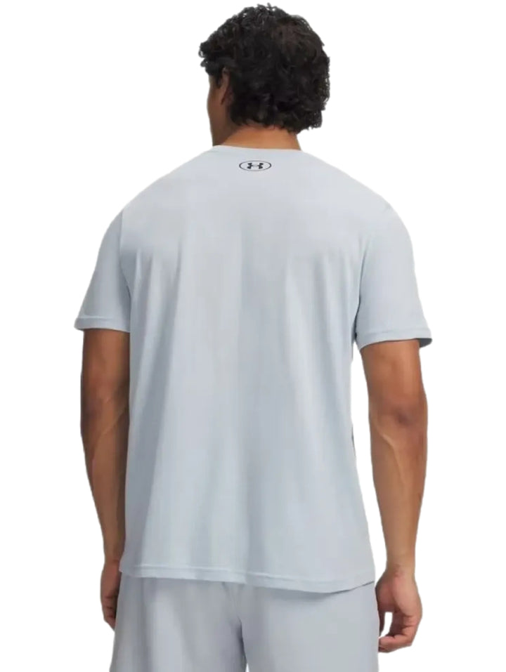 Hombre vistiendo playera deportiva de color gris claro de la marca Under Armour.
