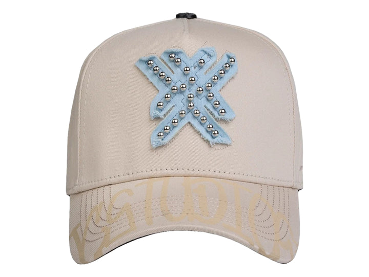 Gorra snapback color beige con un parche azul en forma de estrella decorado con perlas plateadas.
