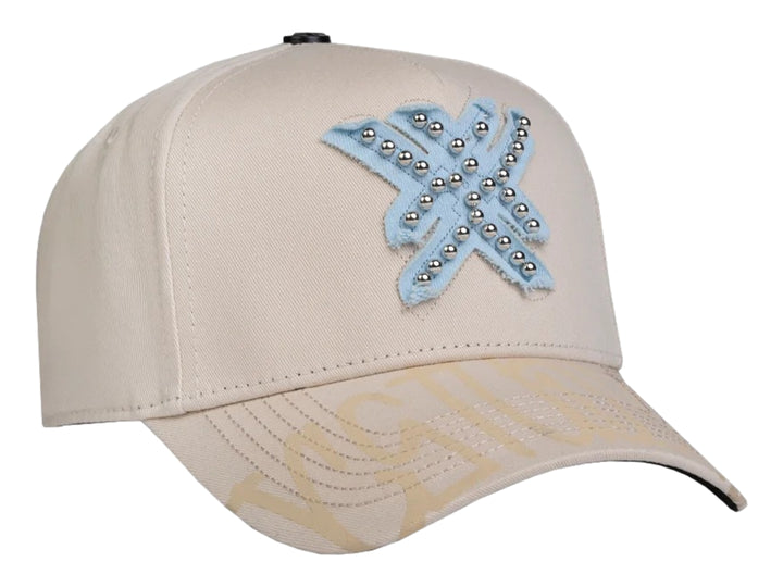 Gorra snapback color beige con un parche azul en forma de estrella decorado con perlas plateadas.