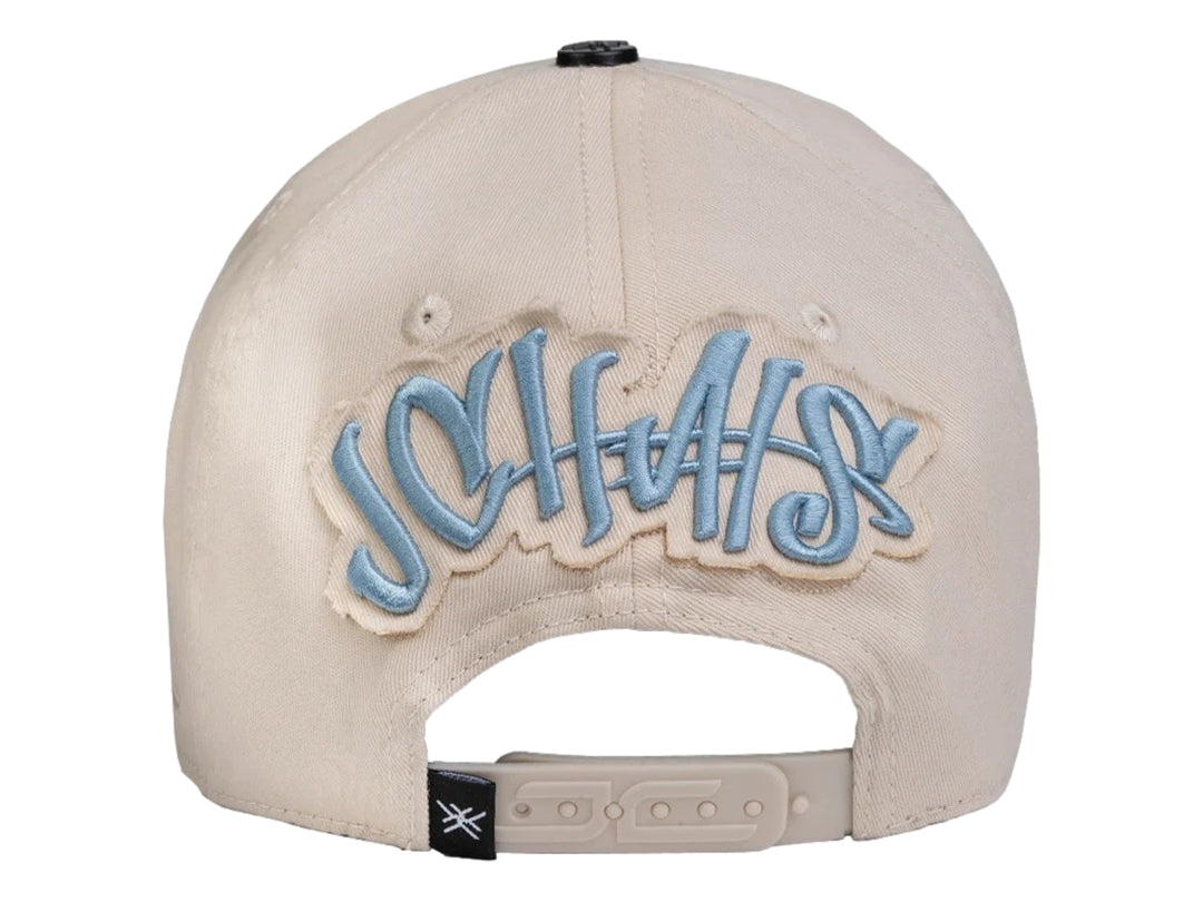 Gorra snapback color beige con un parche azul en forma de estrella decorado con perlas plateadas.