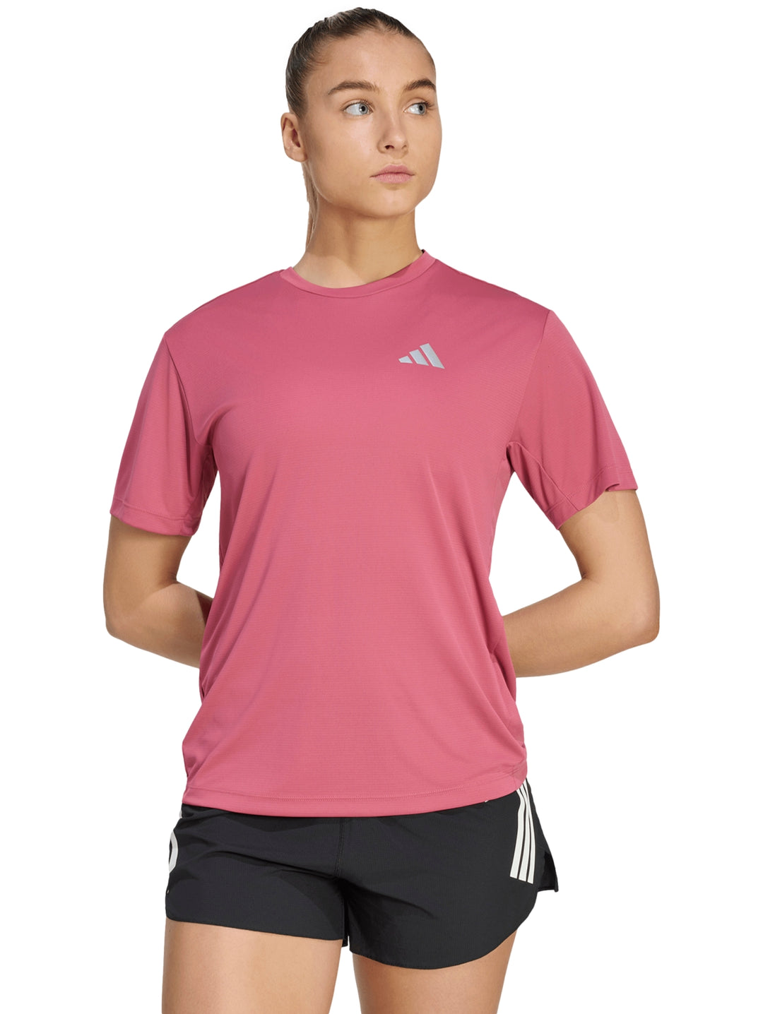 Mujer vistiendo playera deportiva Adidas color magenta y shorts negros.