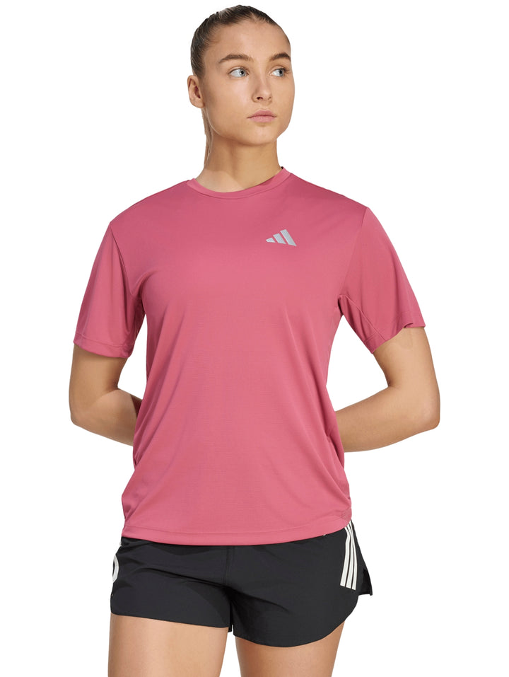 Mujer vistiendo playera deportiva Adidas color magenta y shorts negros.