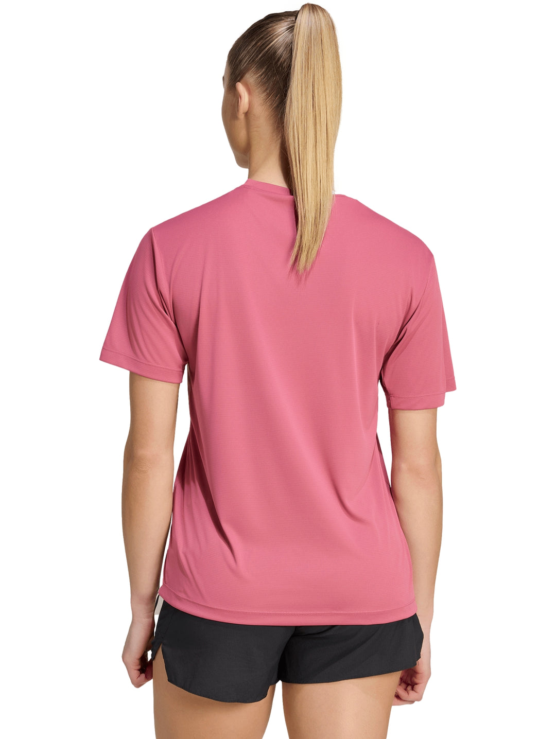 Mujer vistiendo playera deportiva Adidas color magenta y shorts negros.