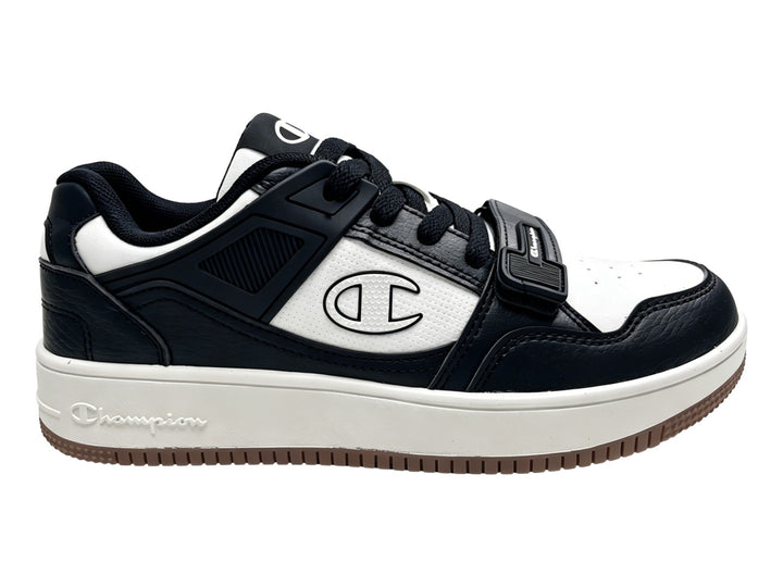 Tenis Champion Ace Cross en colores negro y blanco con suela blanca y detalle de correa velcro.