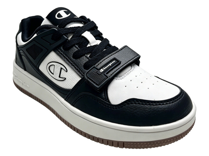 Tenis Champion Ace Cross en colores negro y blanco con suela blanca y detalle de correa velcro.
