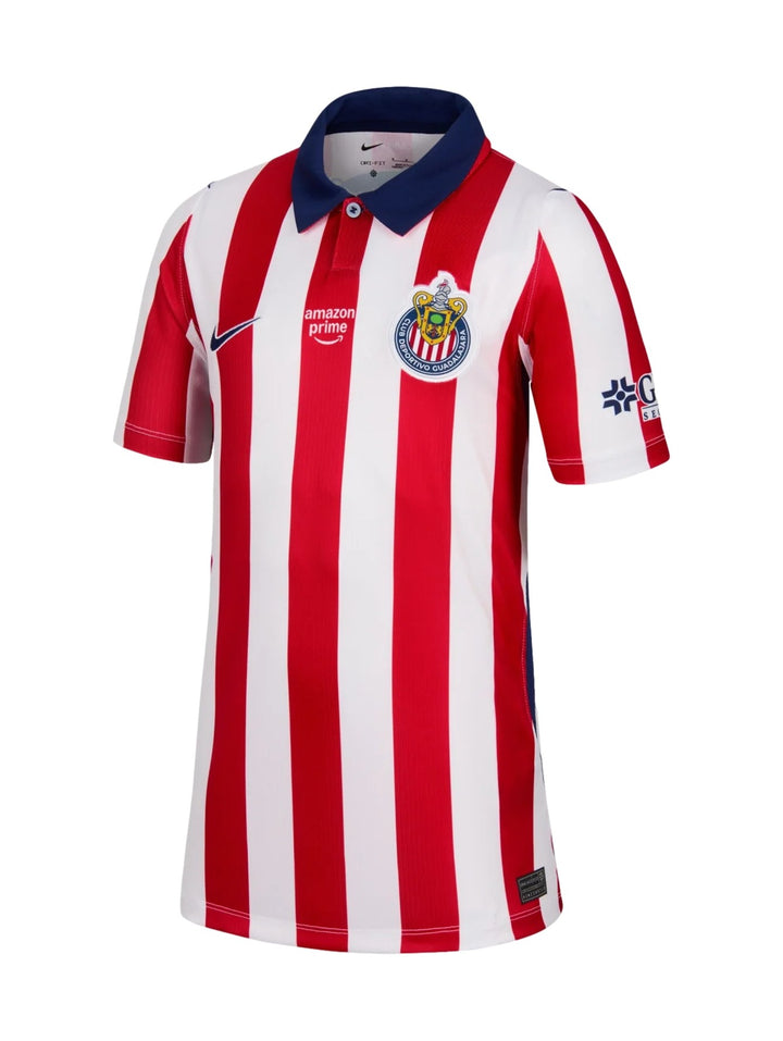 Niña vistiendo playera deportiva Nike del Chivas con rayas verticales rojas y blancas y cuello azul.