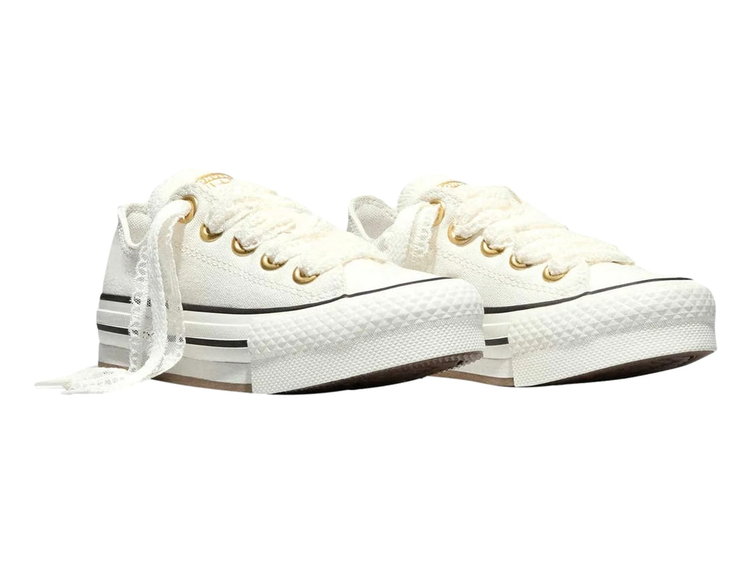 Tenis Converse Chuck Taylor All Star blancos de plataforma con ojillos dorados y suela gruesa.