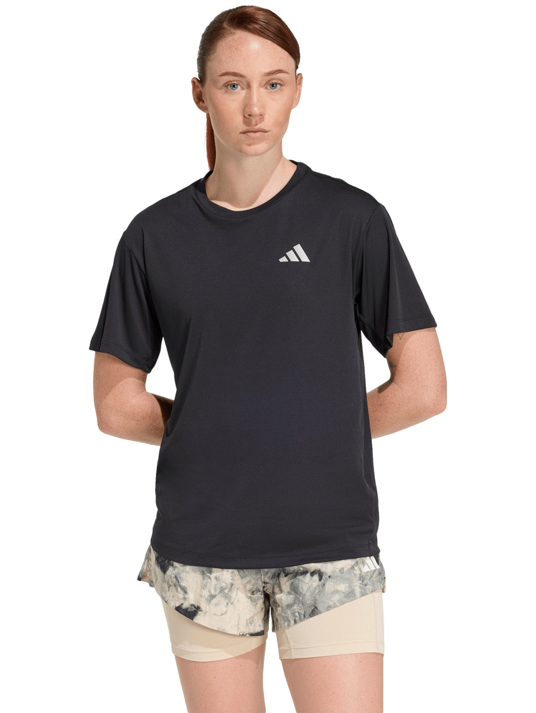 Mujer vistiendo playera deportiva Adidas de color negro con logo blanco en el pecho.