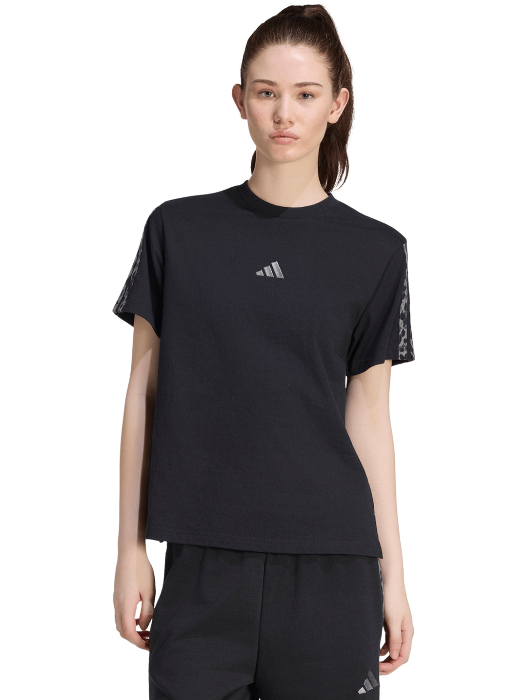 Mujer vistiendo playera deportiva Adidas color negro con estampado en las mangas.