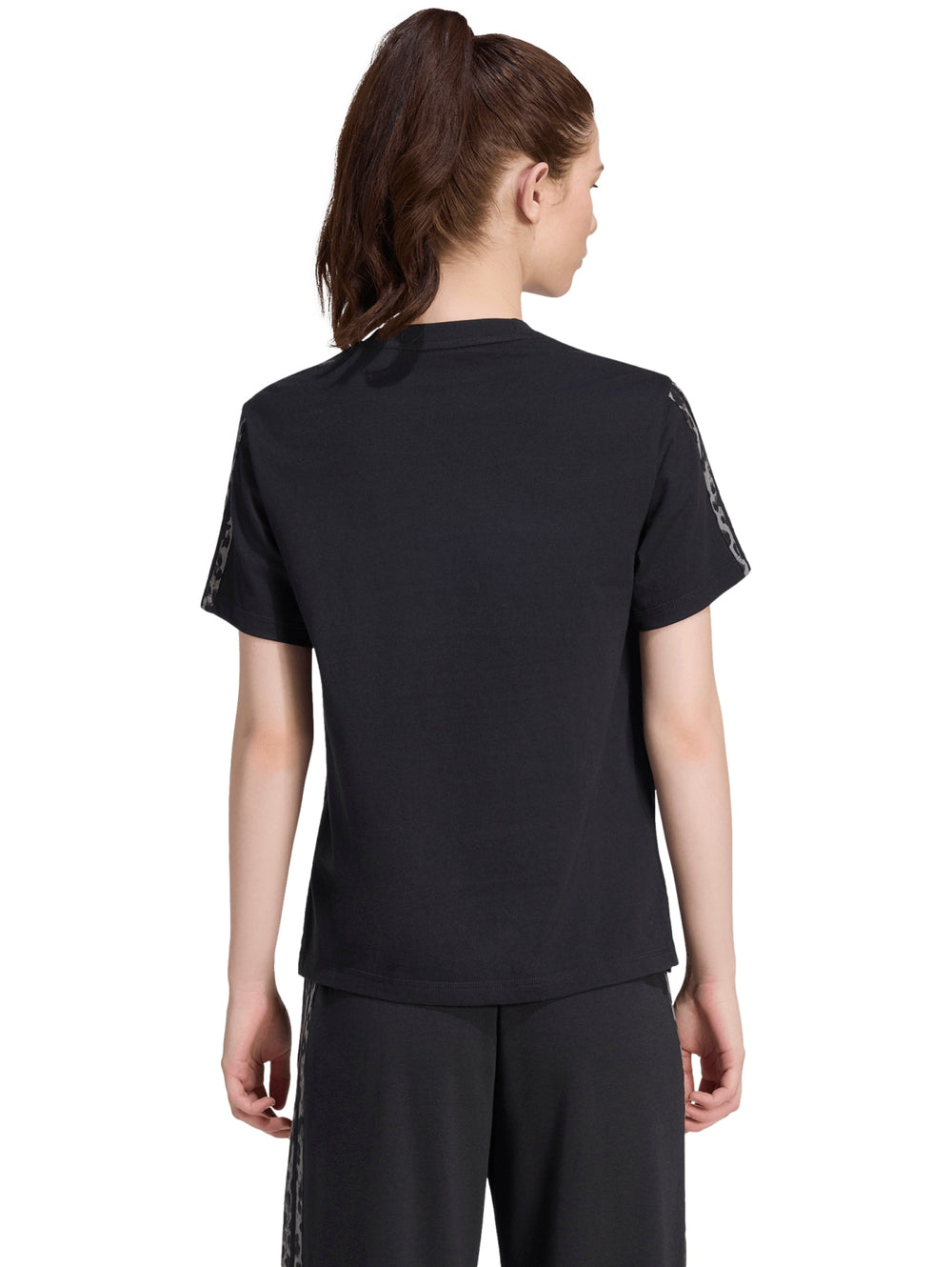 Mujer vistiendo playera deportiva Adidas color negro con estampado en las mangas.