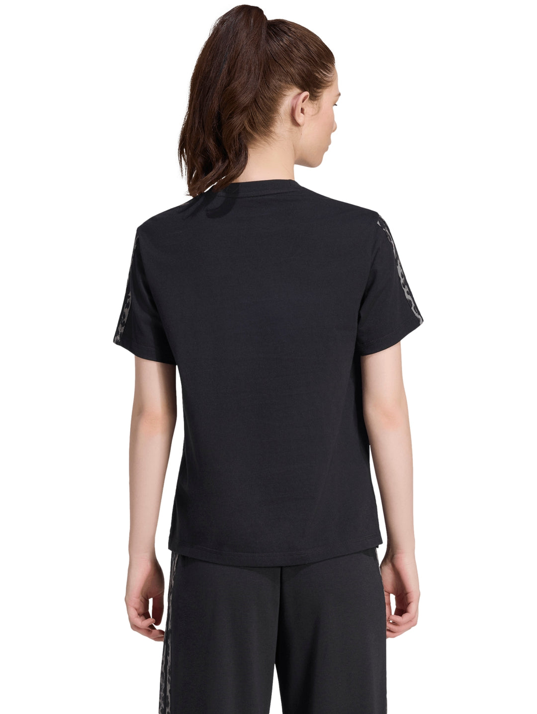 Mujer vistiendo playera deportiva Adidas color negro con estampado en las mangas.