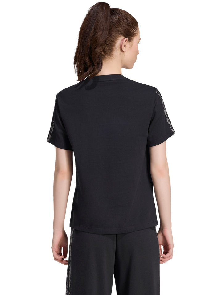 Mujer vistiendo playera deportiva Adidas color negro con estampado en las mangas.
