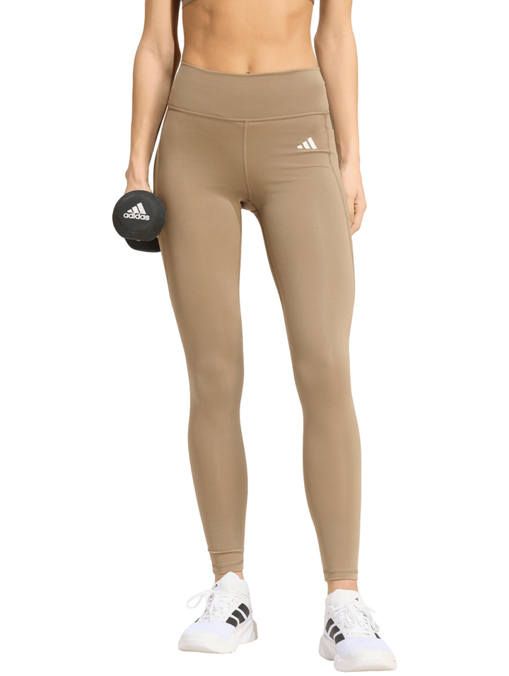 Mujer vistiendo leggings deportivos Adidas color khaki y tenis blancos.