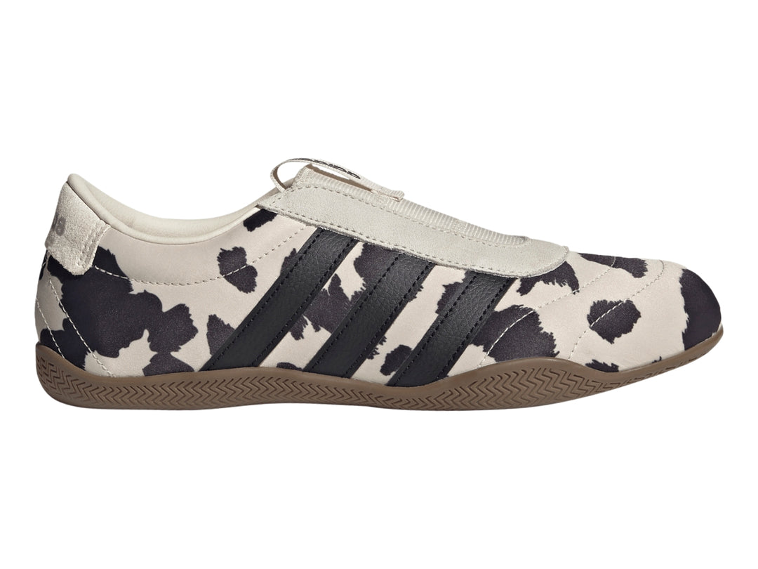 Tenis Adidas Grand Court Lo Slip con estampado de vaca en blanco y negro y suela color marrón.