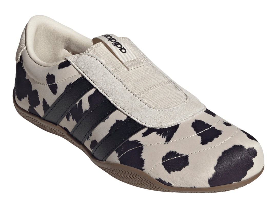 Tenis Adidas Grand Court Lo Slip con estampado de vaca en blanco y negro y suela color marrón.
