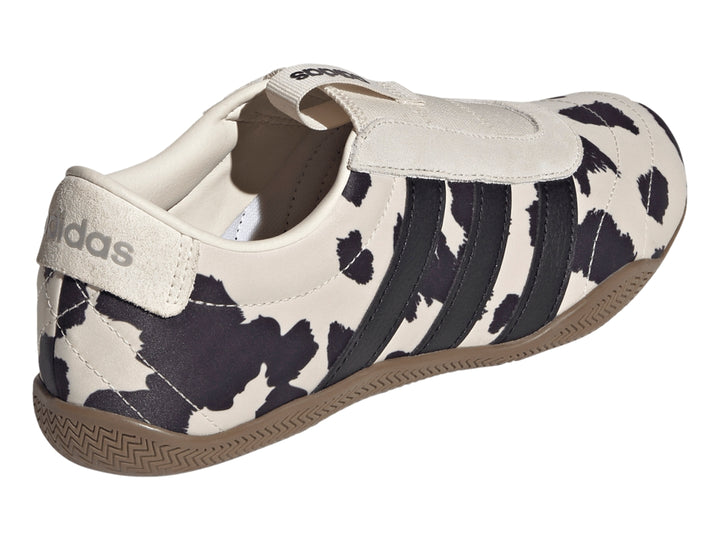 Tenis Adidas Grand Court Lo Slip con estampado de vaca en blanco y negro y suela color marrón.