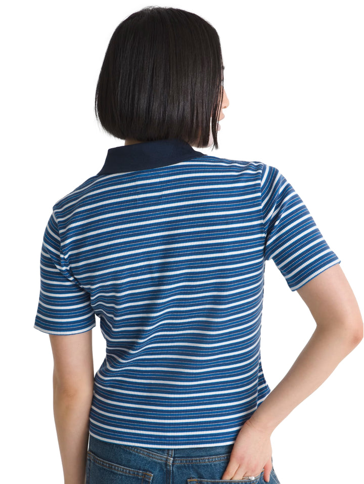 Mujer vistiendo playera polo Vans de rayas azules y blancas con cuello azul marino.