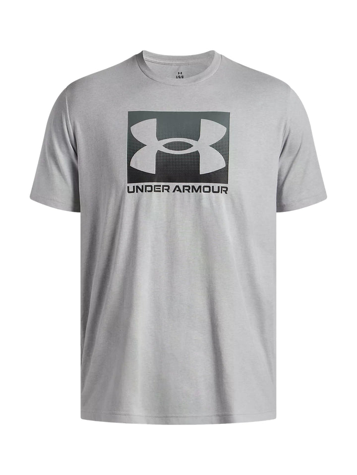 Hombre vistiendo playera deportiva Under Armour de color gris claro con logotipo negro en el pecho.