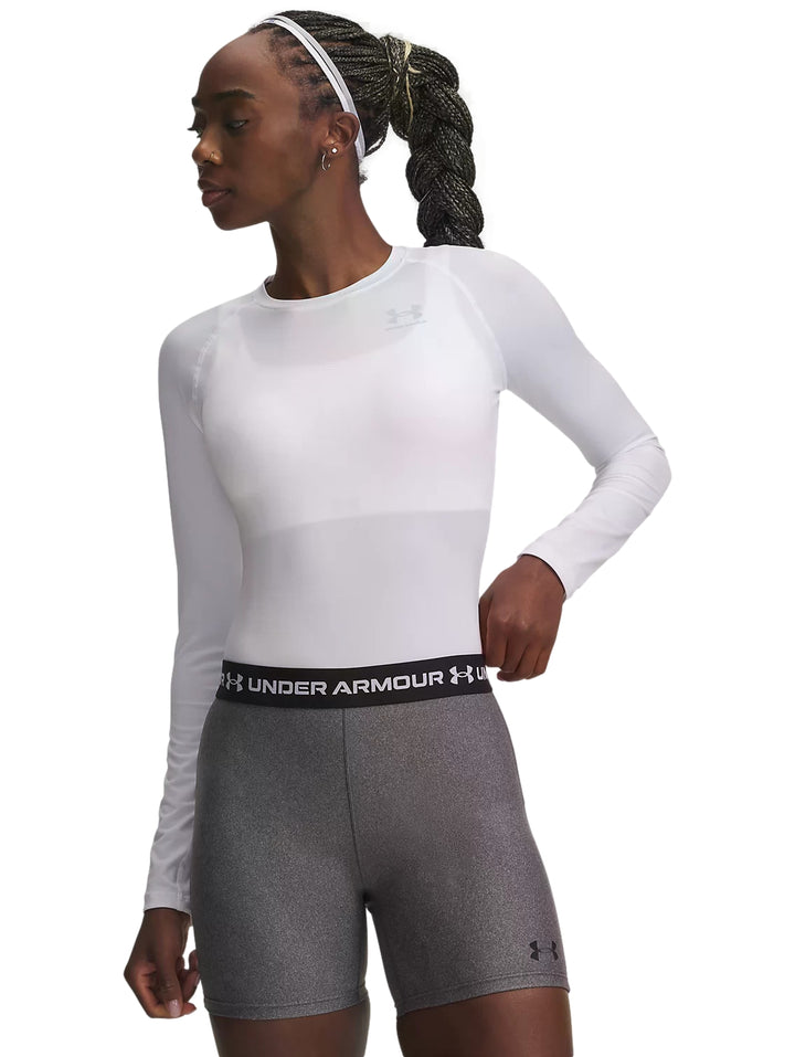 Mujer vistiendo playera deportiva blanca de manga larga y shorts grises Under Armour.