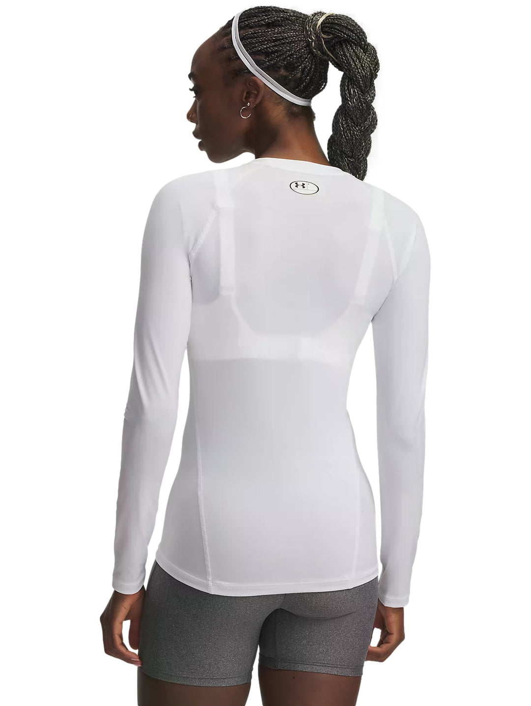 Mujer vistiendo playera deportiva blanca de manga larga y shorts grises Under Armour.