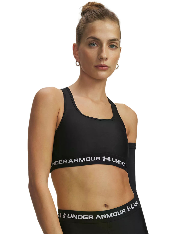 Mujer vistiendo un top deportivo negro de Under Armour con banda blanca en la base.