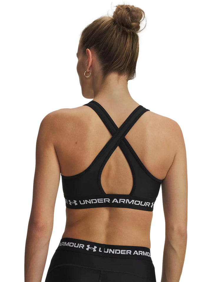 Mujer vistiendo un top deportivo negro de Under Armour con banda blanca en la base.