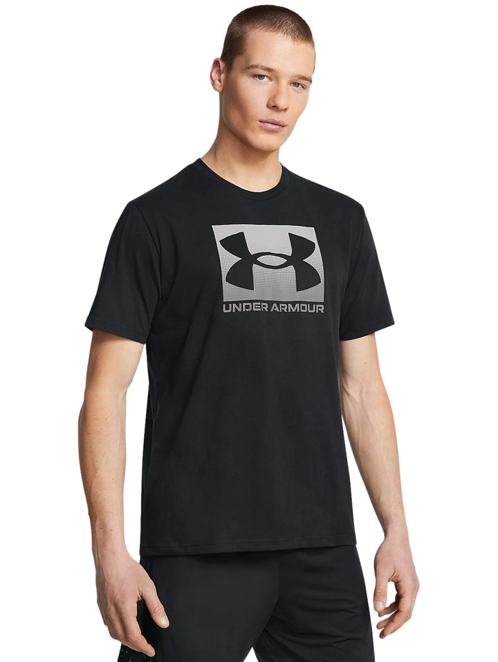 Hombre vistiendo playera deportiva negra de manga corta con logotipo de Under Armour en color gris en el pecho.