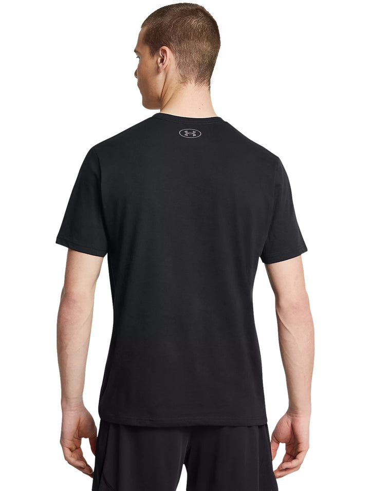 Hombre vistiendo playera deportiva negra de manga corta con logotipo de Under Armour en color gris en el pecho.