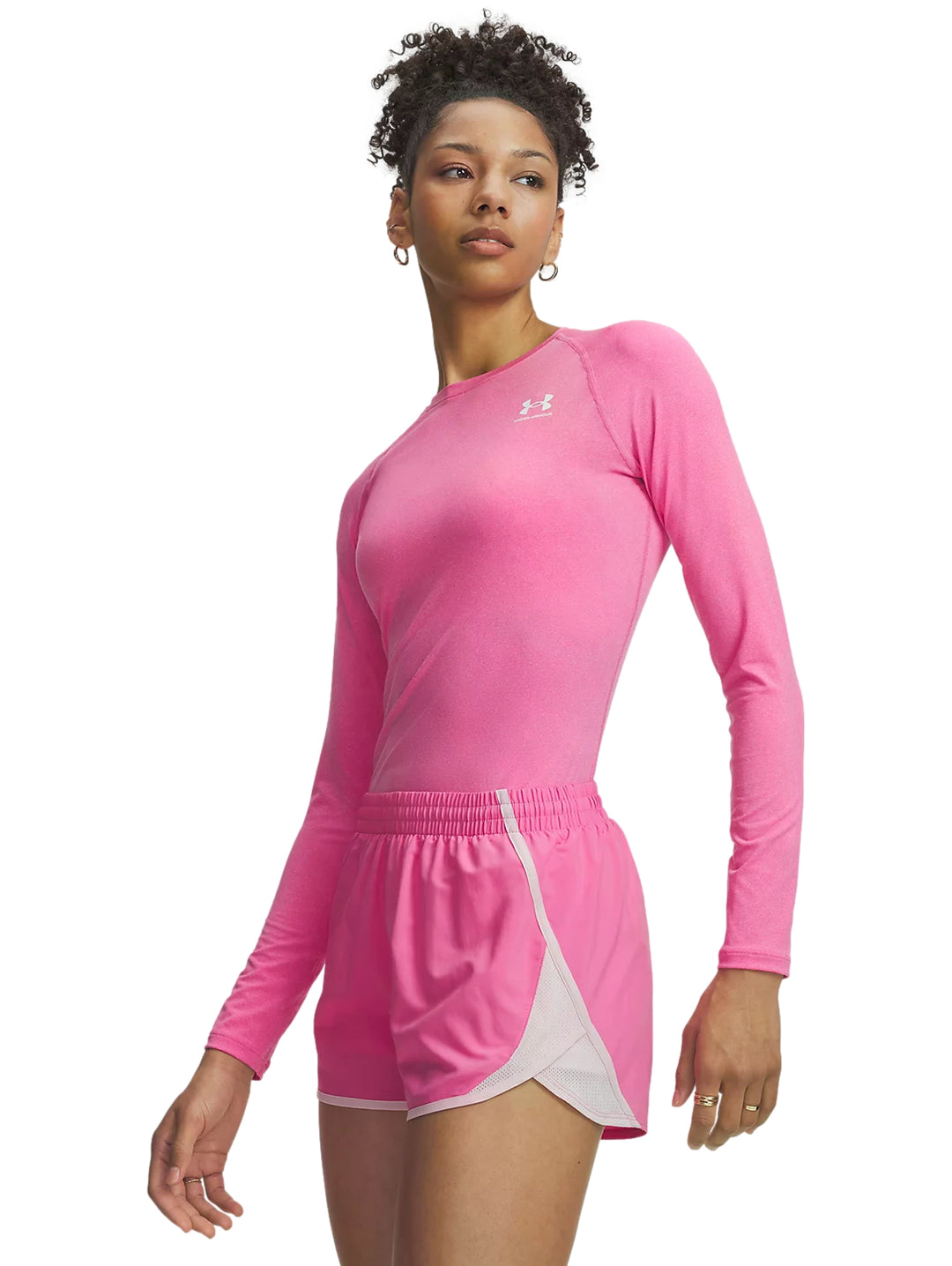 Mujer vistiendo playera deportiva rosa de manga larga y shorts rosas de Under Armour.