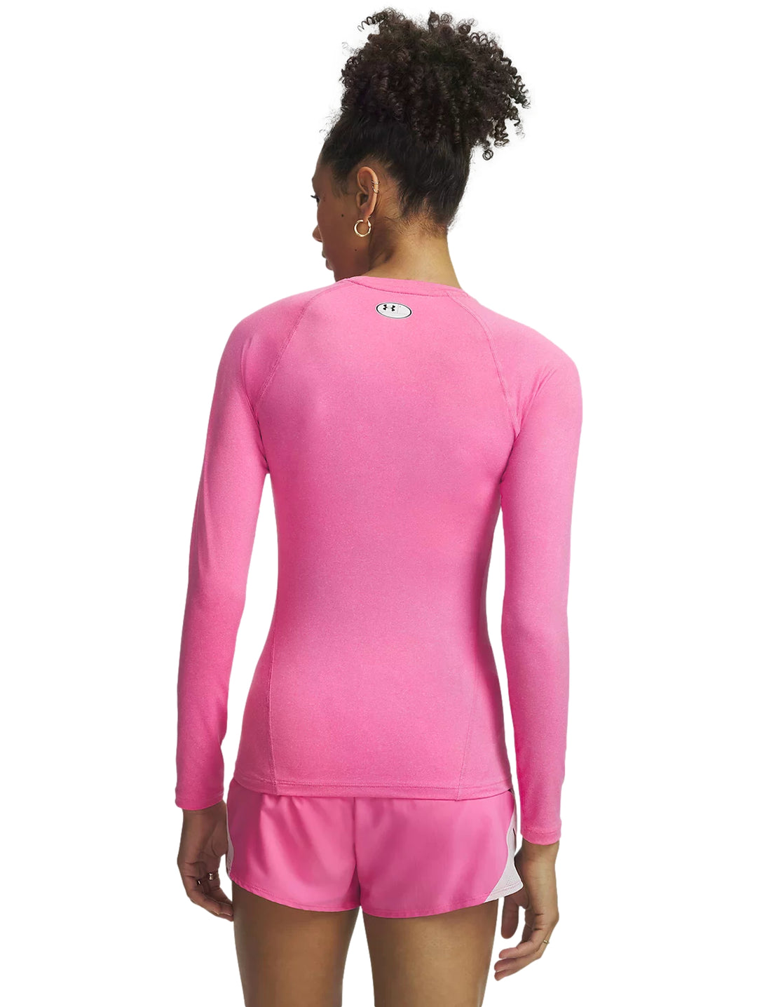 Mujer vistiendo playera deportiva rosa de manga larga y shorts rosas de Under Armour.