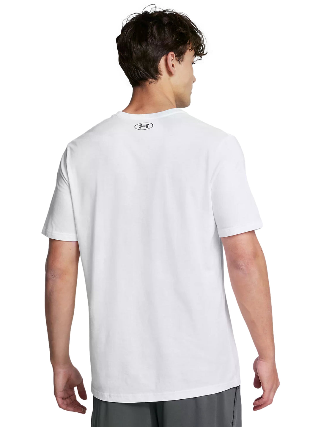 Hombre vistiendo playera deportiva blanca de manga corta con logotipo gris de Under Armour en el pecho.