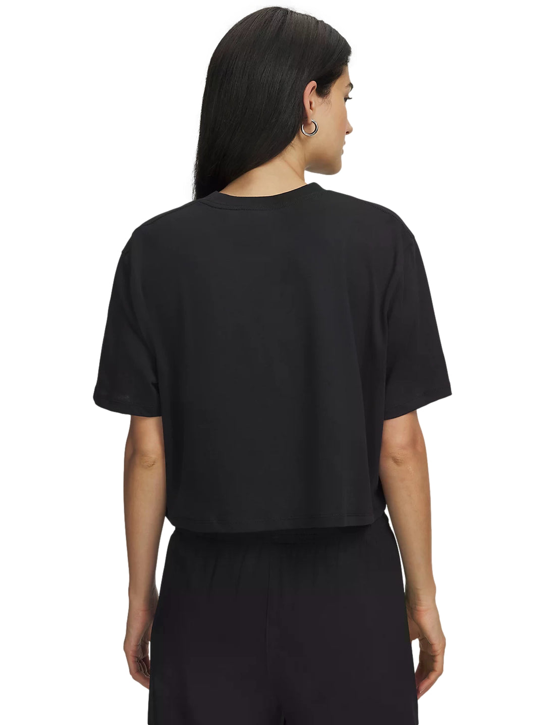 Mujer vistiendo playera deportiva negra de manga corta Under Armour sobre una prenda morada.