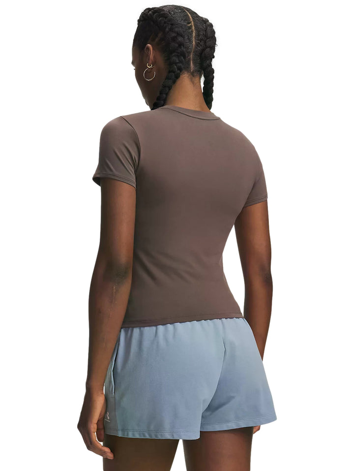 Mujer vistiendo playera deportiva Under Armour ajustada color pimienta y pantalones azul claro.