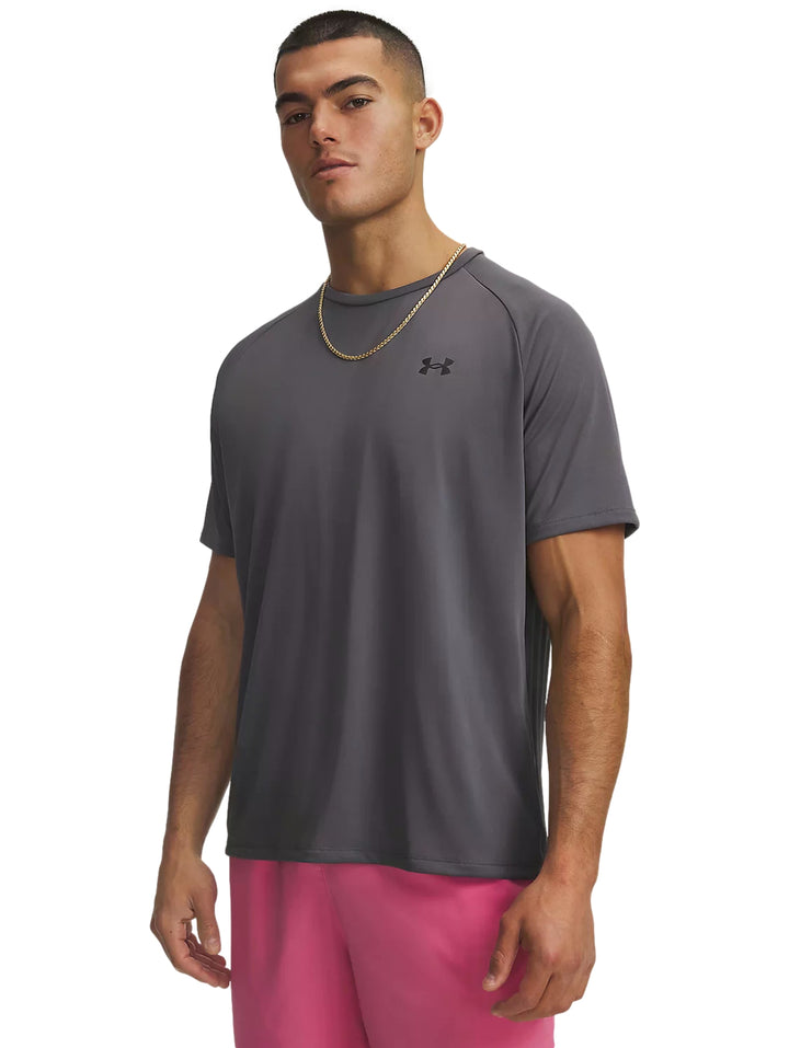 Hombre vistiendo playera deportiva Under Armour color gris y shorts rosas.