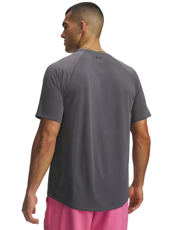 Hombre vistiendo playera deportiva Under Armour color gris y shorts rosas.