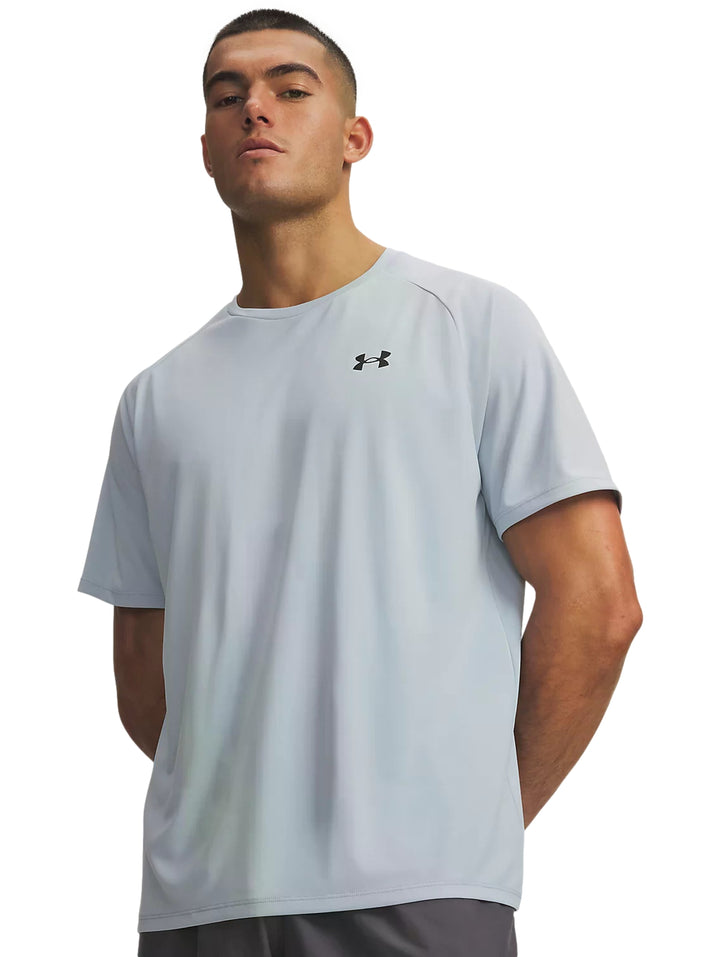 Hombre vistiendo playera deportiva Under Armour de color azul claro con logo negro en el pecho.