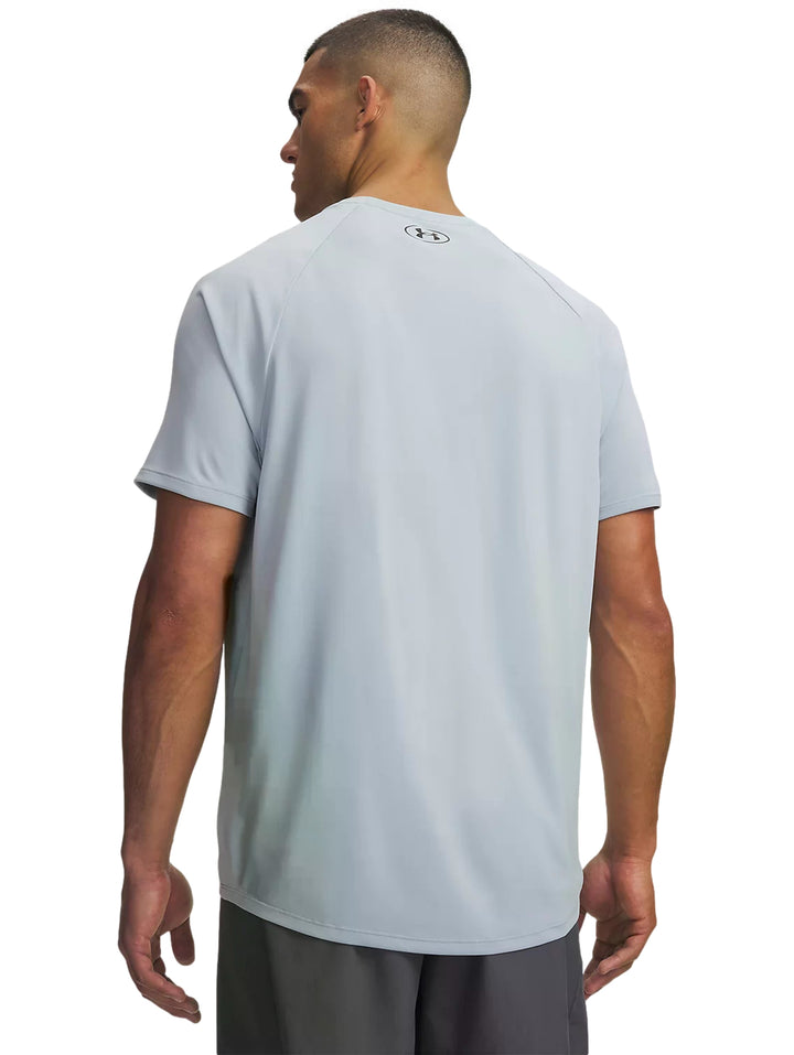 Hombre vistiendo playera deportiva Under Armour de color azul claro con logo negro en el pecho.