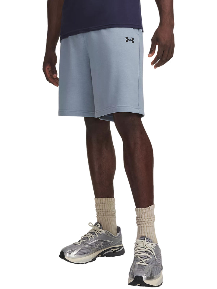Hombre vistiendo shorts deportivos Under Armour color azul claro con calzado deportivo gris.
