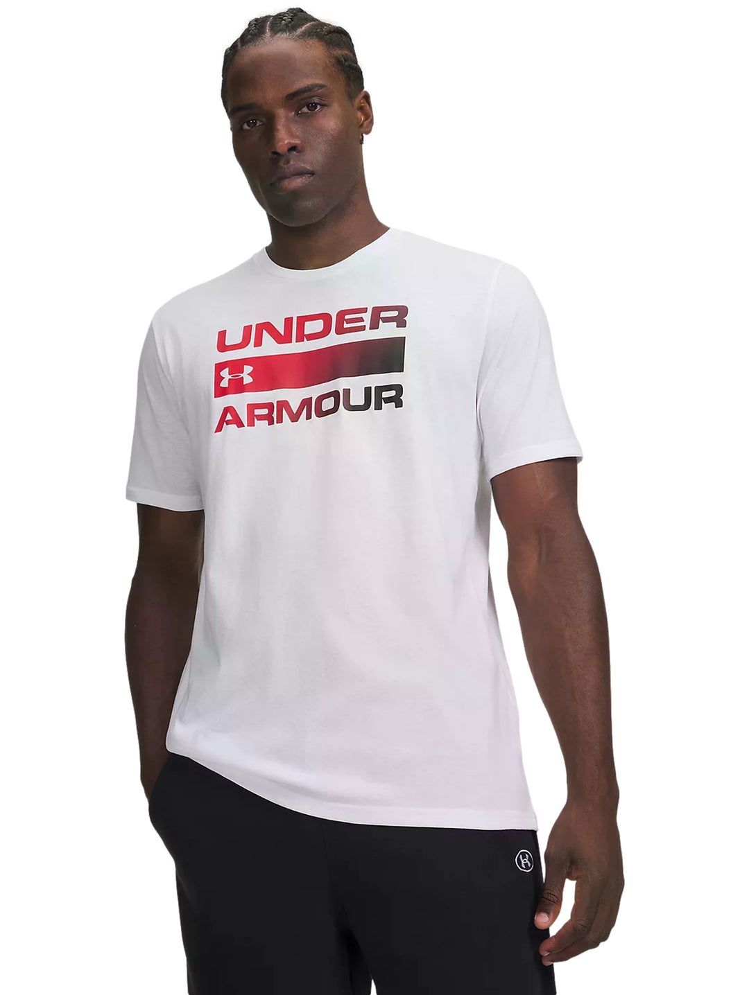 Hombre vistiendo playera blanca de manga corta Under Armour con logotipo rojo en el pecho.