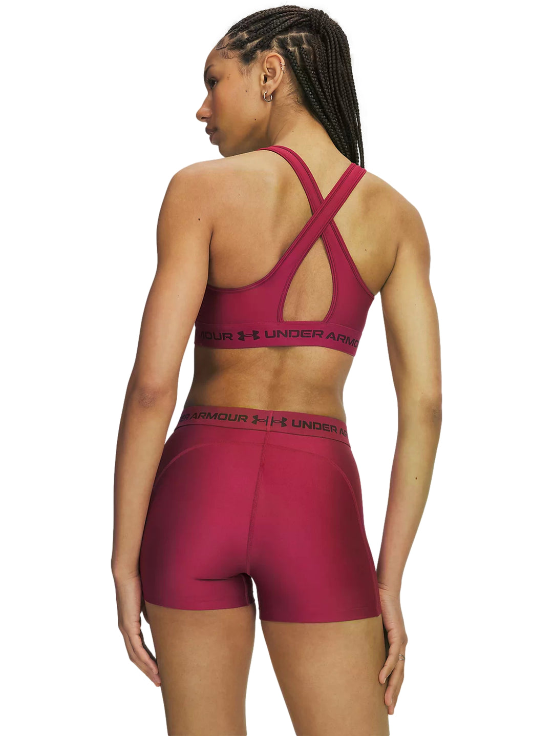 Mujer vistiendo un top deportivo Under Armour color claret con banda elástica en la base.