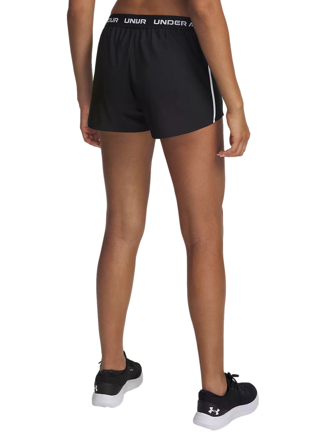 Mujer vistiendo shorts deportivos negros Under Armour con franjas blancas laterales.