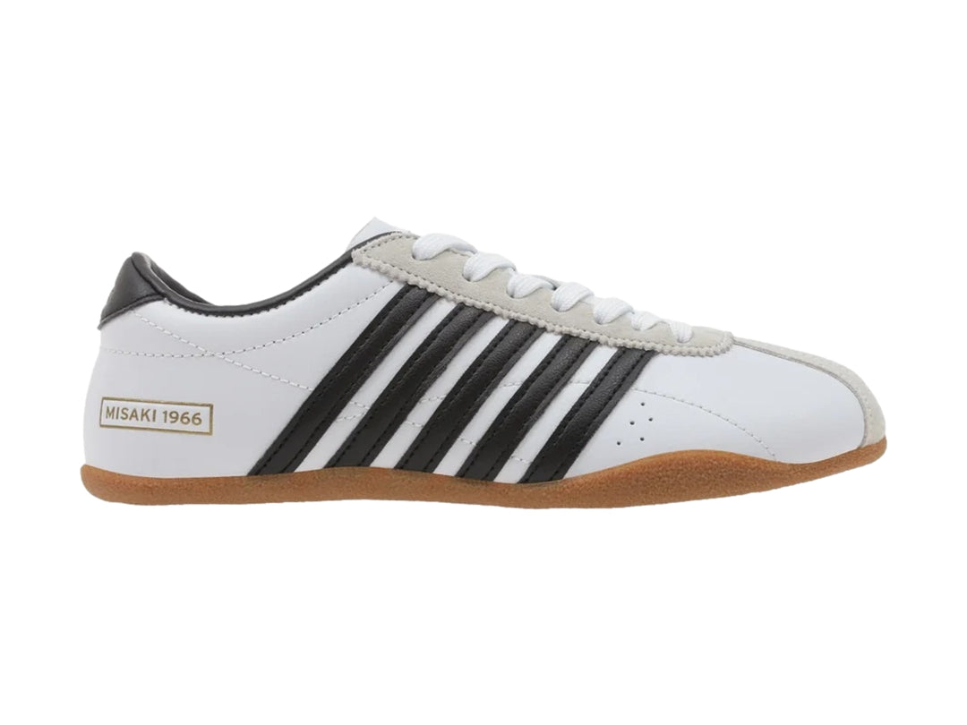 Tenis K-Swiss Misaki V blancos con rayas negras laterales y suela de goma color café.