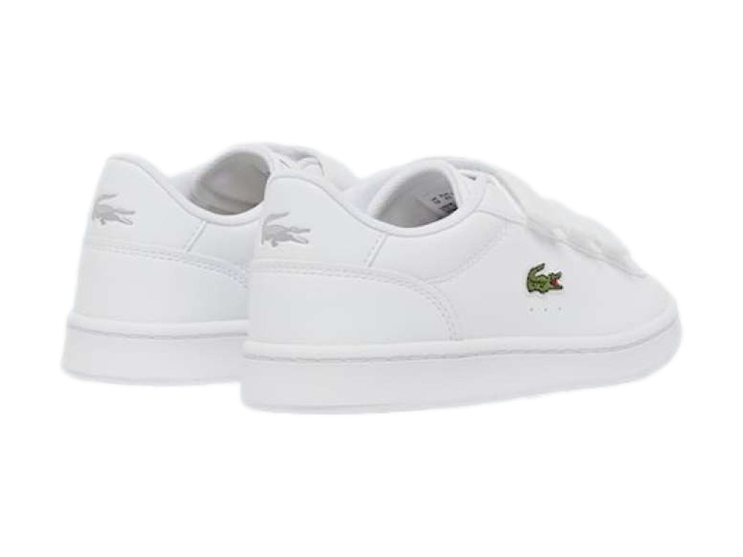 Tenis Lacoste blancos de cuero con cierre de velcro y logotipo del cocodrilo en verde.