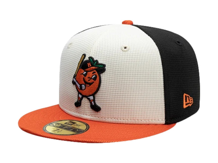Gorra New Era 59Fifty con paneles blanco y negro, visera naranja y bordado frontal de personaje de béisbol.