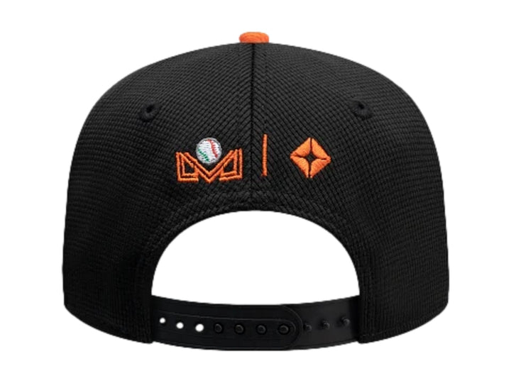 Gorra New Era tricolor en negro, blanco y naranja con bordado de personaje en el frente.