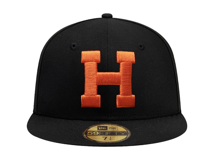 Gorra New Era 59Fifty color negro con letra H bordada en color naranja en el frente y visera plana.