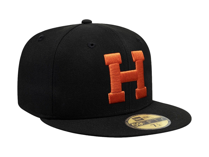 Gorra New Era 59Fifty color negro con letra H bordada en color naranja en el frente y visera plana.