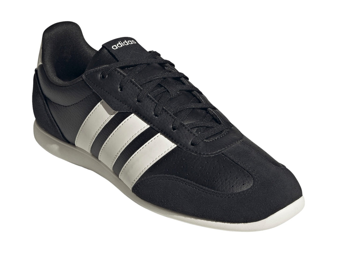 Tenis Adidas Barreda color negro con tres franjas blancas laterales y suela blanca.